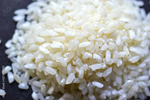 White rice for pilaf spread on a black surface