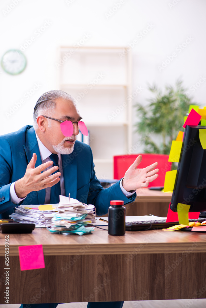 Old employee working in the office in conflicting priorities Old employee working in the office in conflicting priorities