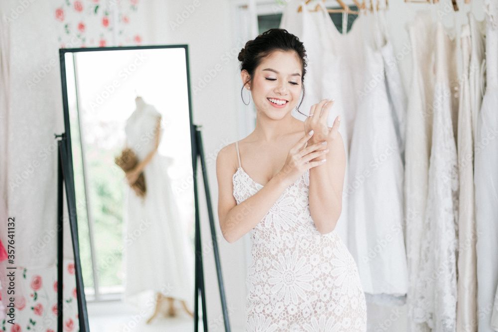 The Asian bride is trying on the wedding dress to dress up to attend the ceremony. with smiling face The Asian bride is trying on the wedding dress to dress up to attend the ceremony. with smiling face