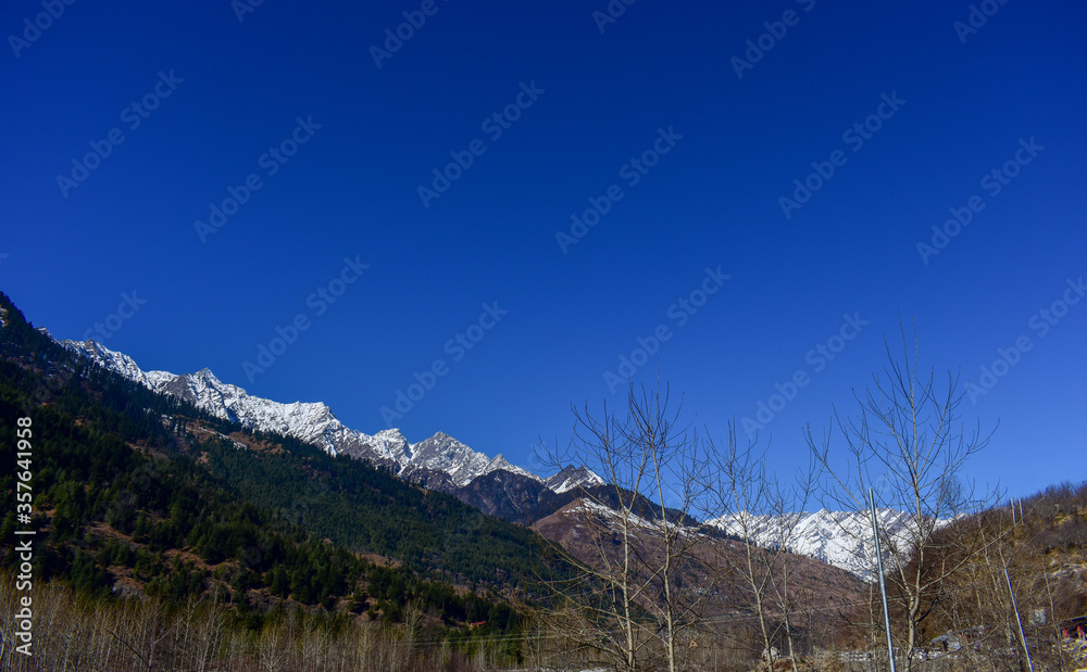 View of Himachal Pradesh, India snow covered mountains over beautiful blue sky.