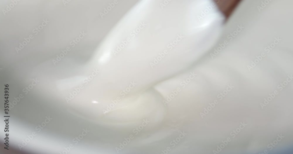 Fresh sour cream stirred with a wooden spatula. Fresh sour cream stirred with a wooden spatula.