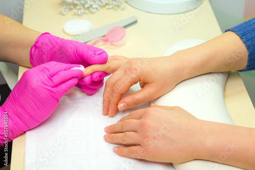 Close Up shot of a woman in a nail salon. Manicure, washing nail polish. Manicurist remove nail polish remover and a cotton pad.