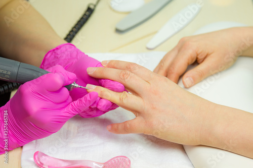 Beautician making hardware manicure. woman hands receiving nail procedure in beauty salon.