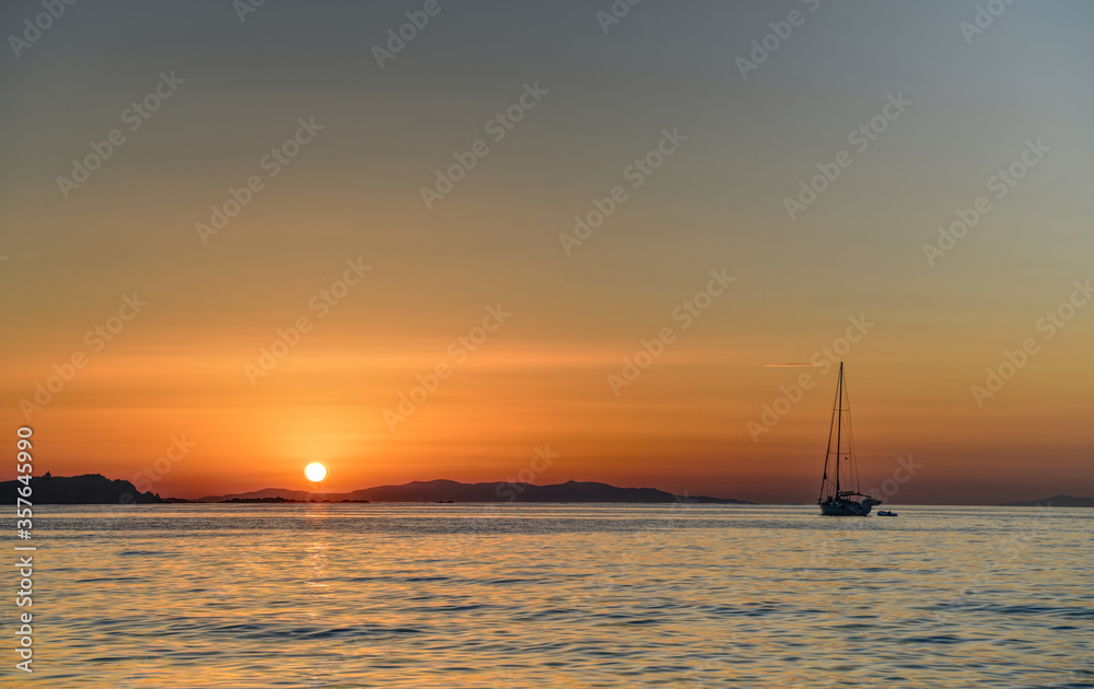 Beautiful sunset on ocean cost of tropical island with single boat in foreground.