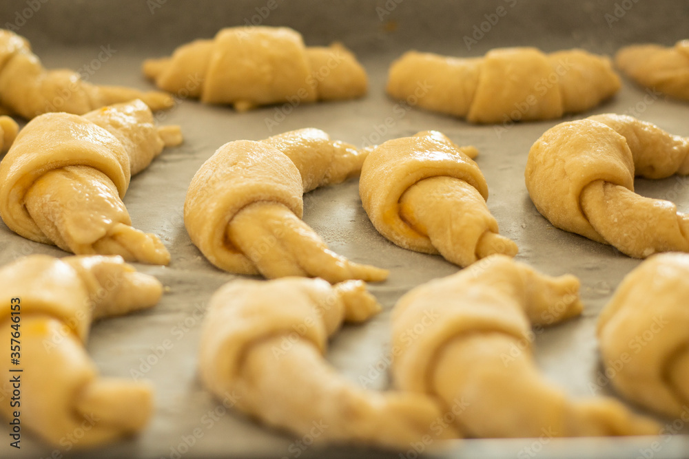 Raw marmalade croissants on paper before baking, close up, side view.