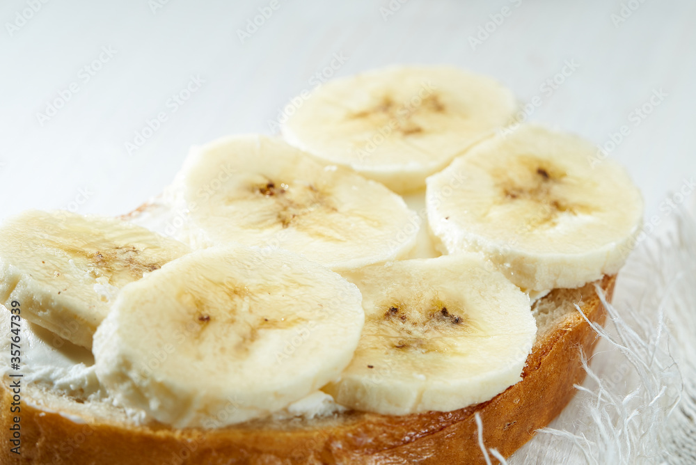 Sandwich with banana slices close up on white wooden table. Sandwich with banana slices close up on white wooden table.