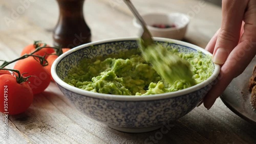 Mashing avocado in bowl with a fork. Preparing vegetarian avocado sauce. Cooking healthy food photo