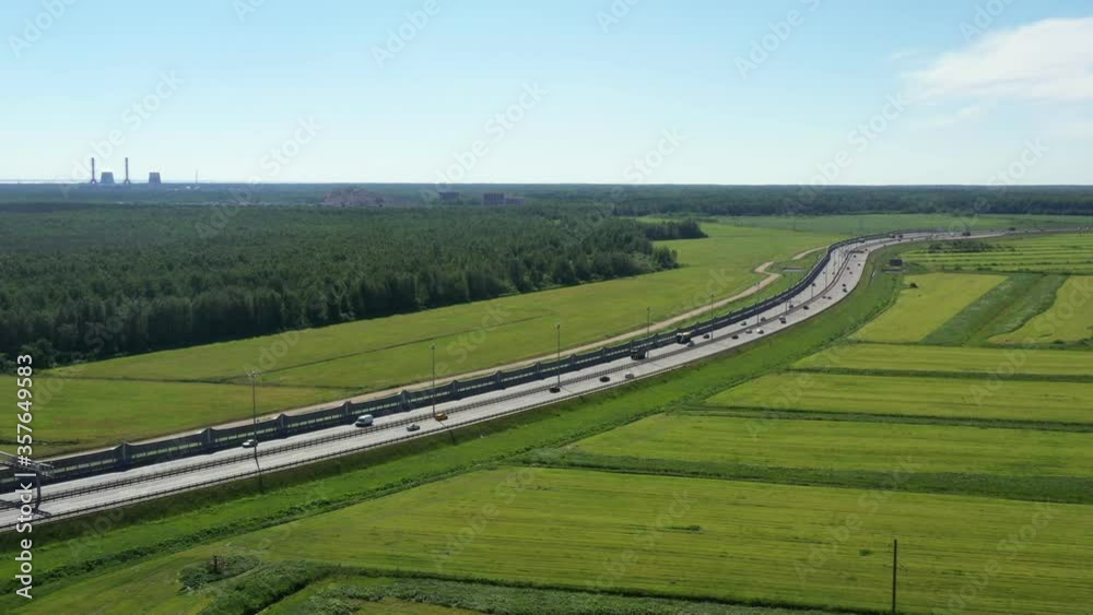 Asphalt ringroad. Speedway with cars through green field near forest. Aerial view from drone Asphalt ringroad. Speedway with cars through green field near forest. Aerial view from drone