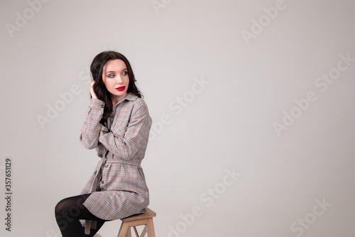 Beautiful sexy girl in a shirt sits on a chair in a photo studio Copy space