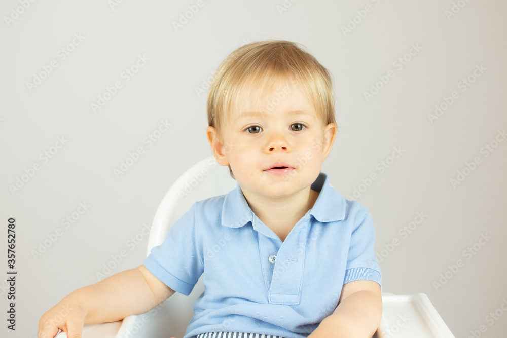 Blond baby with blue polo shirt sitting and smiling Blond baby with blue polo shirt sitting and smiling