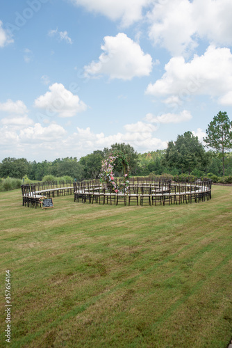 Unique round spiral chair pattern wedding ceremony setting at rolling hills countryside with brown chiavari chairs and white cushions