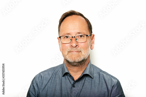 Close up portrait of middle age man taken on white background, wearing grey shirt and glasses © annanahabed