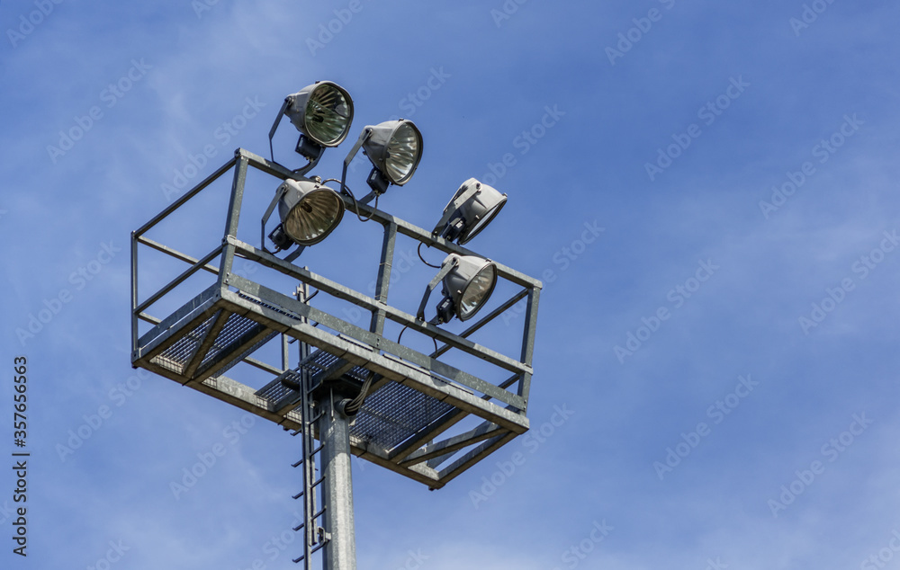 Floodlight mast in the school stadium in front of blue sky Floodlight mast in the school stadium in front of blue sky