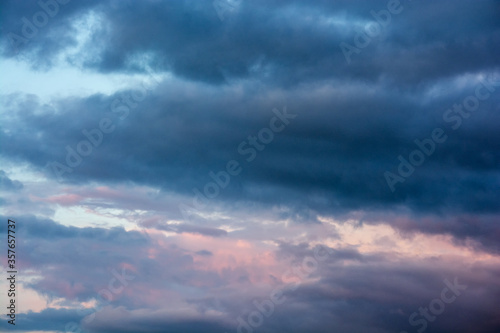 Storm clouds in the blue sky. Spring thunderstorm. The last sun's rays at sunset. Calm before the storm.