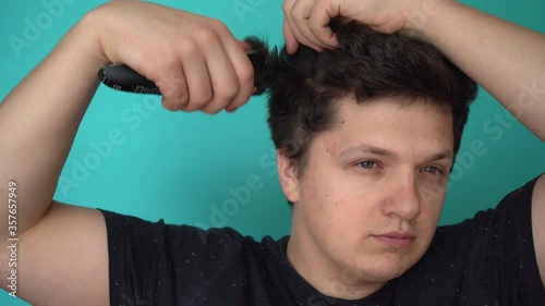 Brunette begins to cut himself with an electric trimer. Blue background