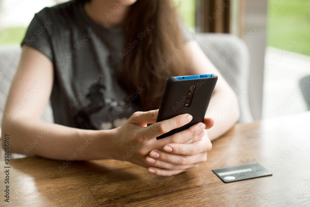 Online payment. Female hands holding phone for online shopping over the desk. Indoor close-up. Online shopping concept Online payment. Female hands holding phone for online shopping over the desk. Indoor close-up. Online shopping concept