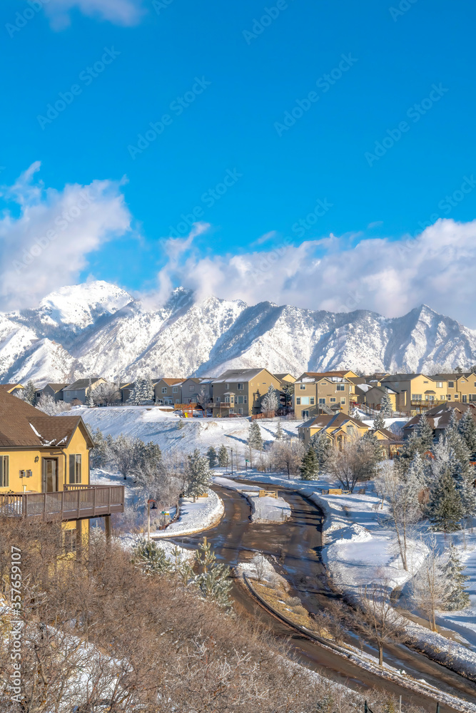 Road along mountain homes with Wasatch peaks and cloudy blue sky views