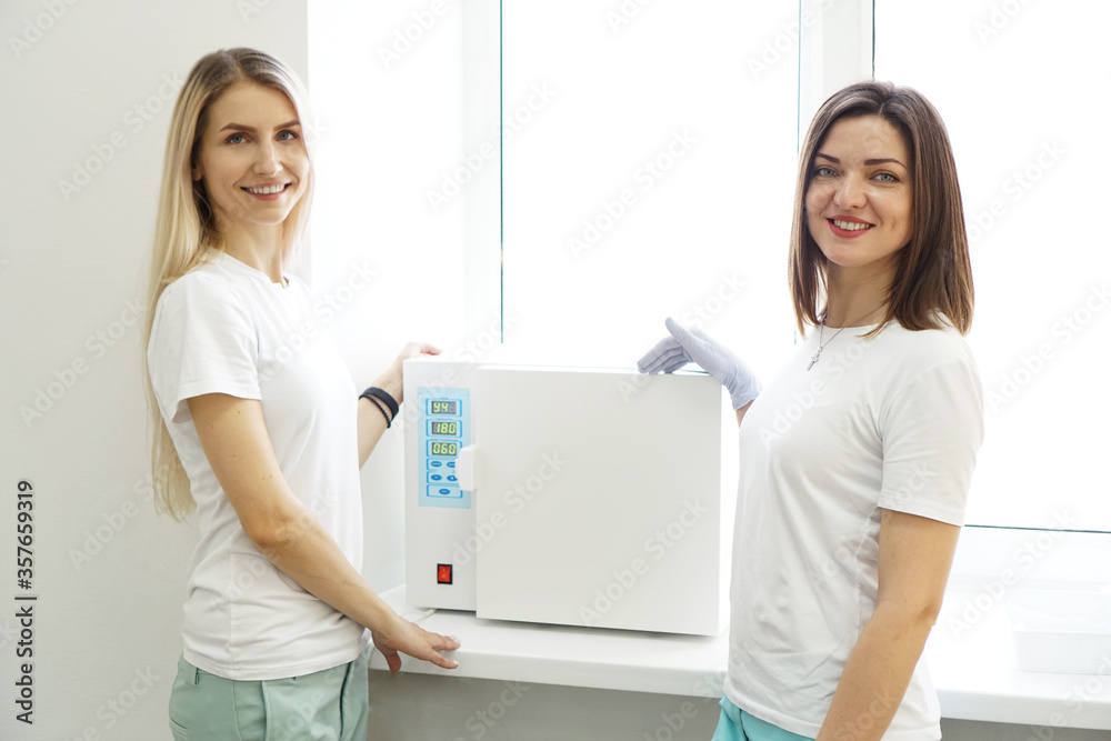 Dry heat for sterilization instruments. Two friendly women - masters of a beauty salon Dry heat for sterilization instruments. Two friendly women - masters of a beauty salon
