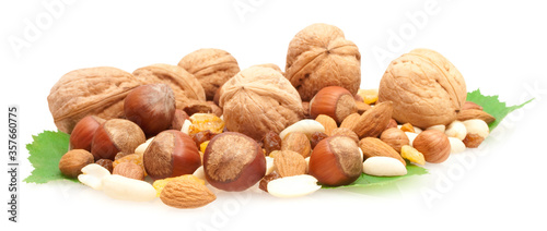 collection of nnuts and dried fruits on green leaves isolated on white background