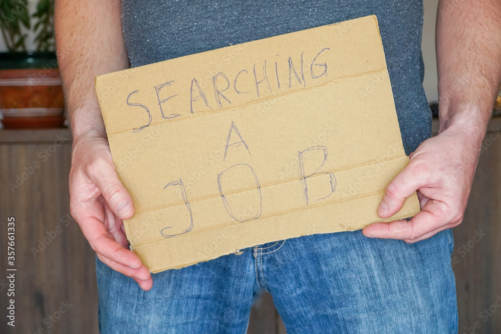 Man in jeans holds a cardboard in his hands search a job