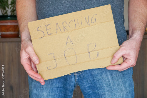 Obraz na płótnie Man in jeans holds a cardboard in his hands search a job w salonie