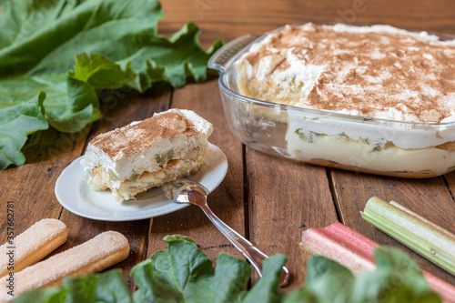 selbstgemachtes Tiramisu mit Rhabarber, Creme, Sahne, Zimt, Löffelbiscuit und Mascarpone auf einem Tisch aus Holz