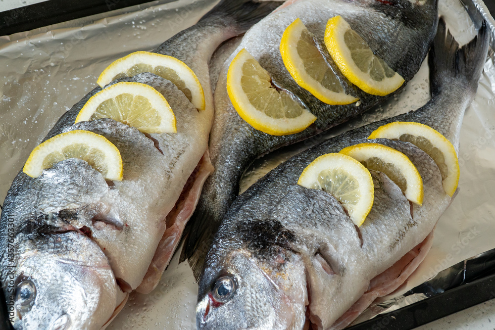 Fresh dorada fish with lemon on a baking sheet. Dorado's head close-up. Soft focus