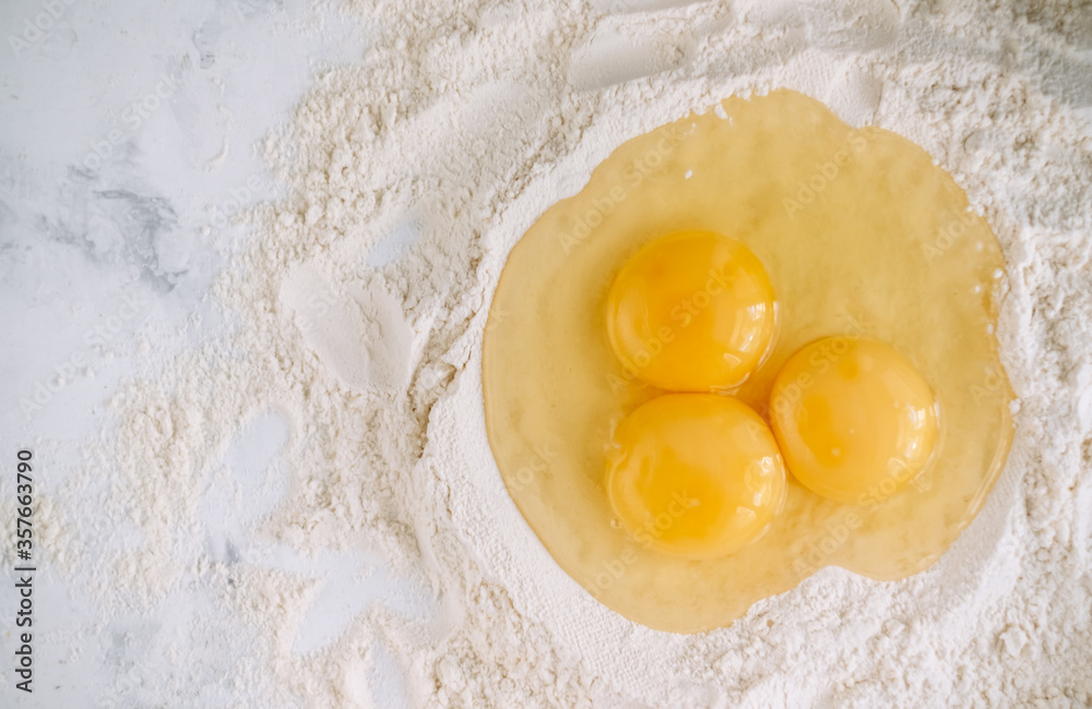Chicken eggs in flour on the kitchen table, ingredients. Preparation for baking, culinary recipes. Copy space. Chicken eggs in flour on the kitchen table, ingredients. Preparation for baking, culinary recipes. Copy space.