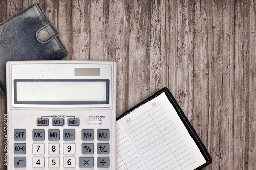 Office flat lay composition with calculator, address book and black purse on brown wooden table background with top view. Accountant paperwork concept photo