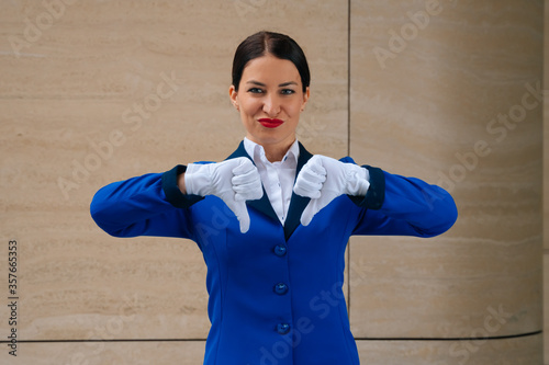 Tricky girl flight attendant shows indignation dislike. Flight attendant in white gloves indignant, thumbs down