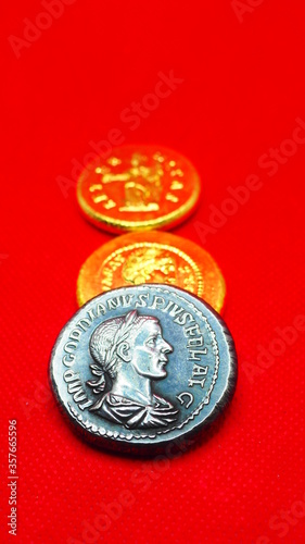 Silver and gold roman coins on red background photo