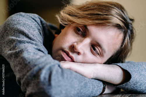 Handsome young man with blond hair looks thoughtfully to the side, dreams and goals in his thoughts, pensive and dreamy shot