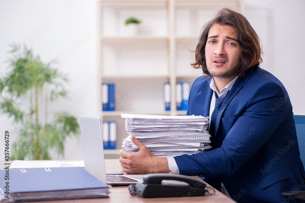 Young male employee unhappy with excessive work Young male employee unhappy with excessive work