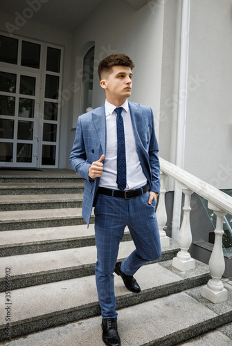 Portrait of a serious young handsome man in a blue suit and tie clasp fastener