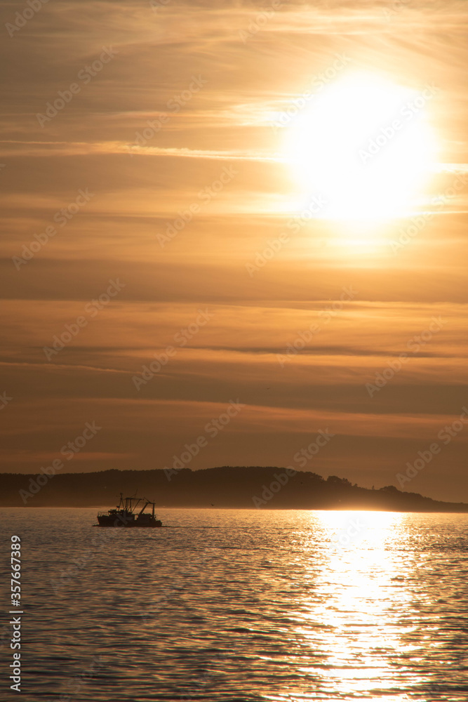 Fishing boat returning home at sunset.