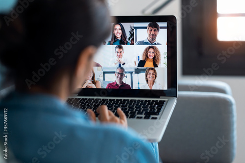 Business woman speaking on video call with diverse colleagues on online briefing with laptop on sofa at home. photo