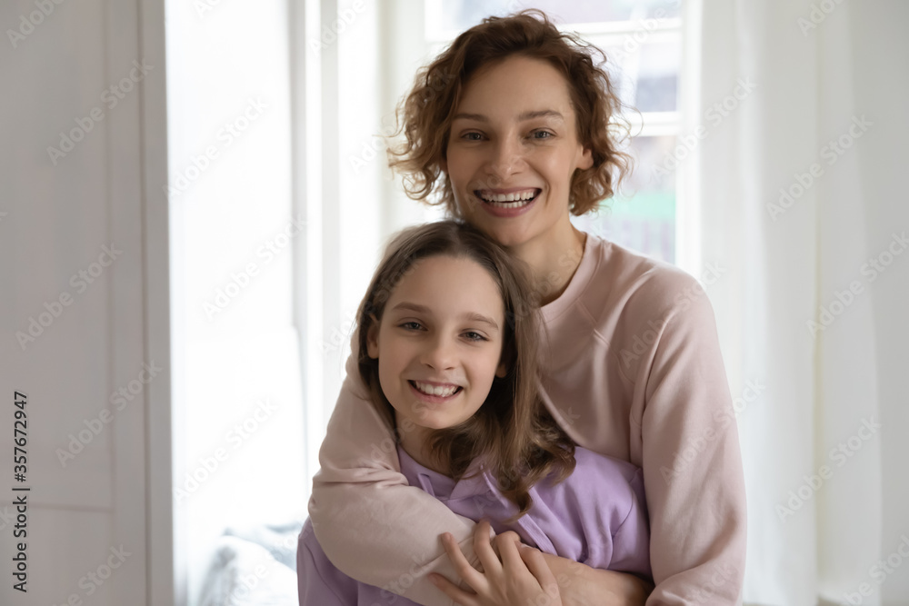 Portrait of smiling young Caucasian mother and teenage daughter hug and cuddle, happy mom and teen girl child stand embracing, show love and understanding in relationships, family bonding concept Portrait of smiling young Caucasian mother and teenage daughter hug and cuddle, happy mom and teen girl child stand embracing, show love and understanding in relationships, family bonding concept