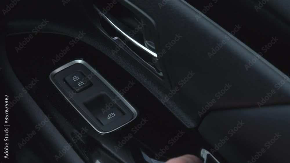 Hand operating the window switch control of a car by pressing the button located on the door. Hand operating the window switch control of a car by pressing the button located on the door.