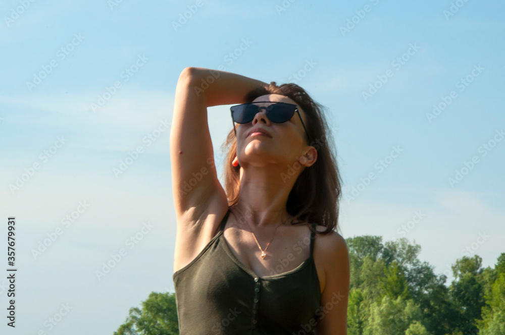 Close-up pretty woman by the river on a summer sunny day. Rest in the summer. Beauty and happiness concept Close-up pretty woman by the river on a summer sunny day. Rest in the summer. Beauty and happiness concept