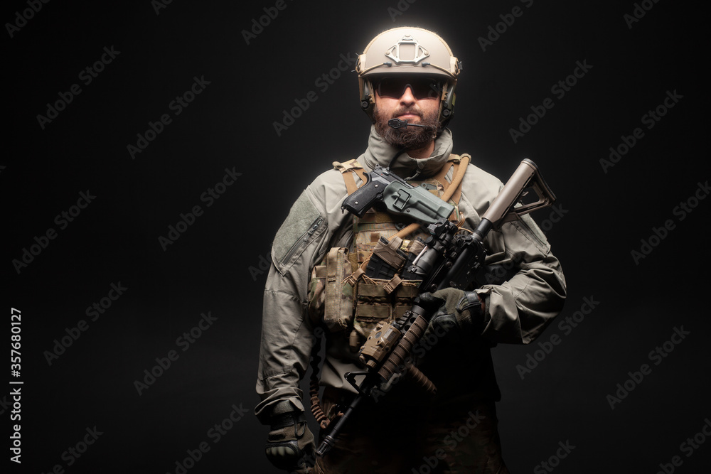 USA soldier in a military suit with a rifle against a dark background, an American commando with a gun at night
