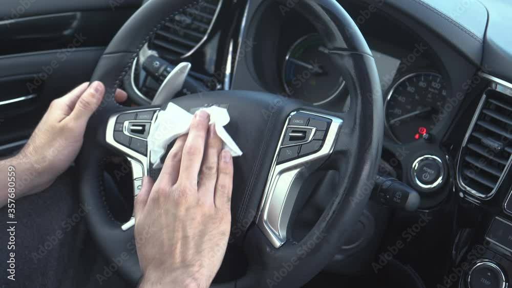 Cleaning the steering wheel of a car using an antivirus antibacterial wet wipe to protect himself from bacteria and virus. Cleaning the steering wheel of a car using an antivirus antibacterial wet wipe to protect himself from bacteria and virus.