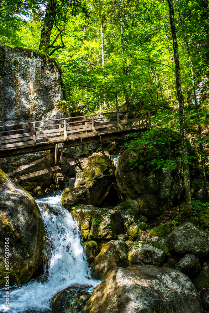 Fototapeta premium Hiking Trail With Wooden Bridge Over Waterfall Through Green Canyon At Myrafälle In Austria