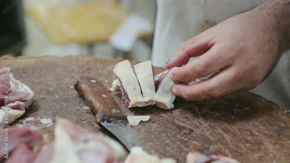 A real butcher from the city meat market cuts up the ribs of a sheep with an axe A real butcher from the city meat market cuts up the ribs of a sheep with an axe