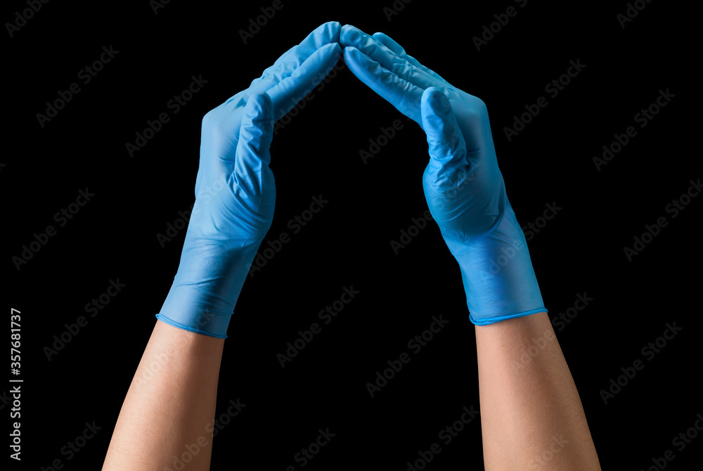Doctor's hand in sterile medical gloves showing heart shape isolated on black