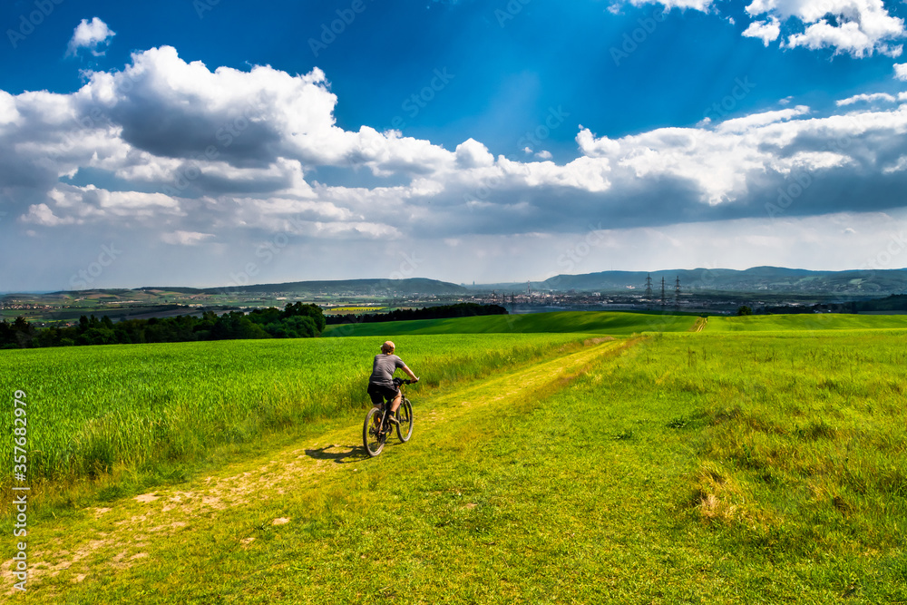 Man Rides Mountainbike In Rural Landscape In Front Of Skyline Of Vienna In Austria Man Rides Mountainbike In Rural Landscape In Front Of Skyline Of Vienna In Austria