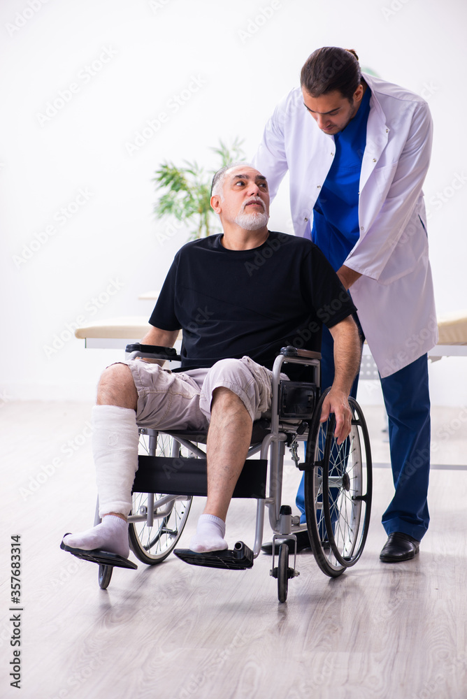 Old injured man visiting young male doctor traumatologist