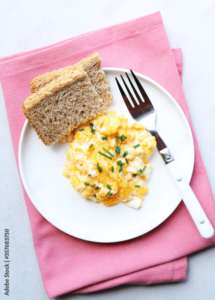 Scrambled eggs on a white plate. Healthy food or breakfast concept.