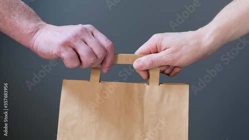 Close up hold in hand brown clear empty blank craft paper bag for give takeaway