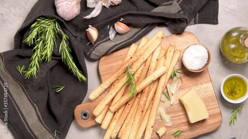 Fresh baked homemade grissini bread sticks in vintage metal grid box with olive oil and rosemary herbs over kitchen counter top. photo