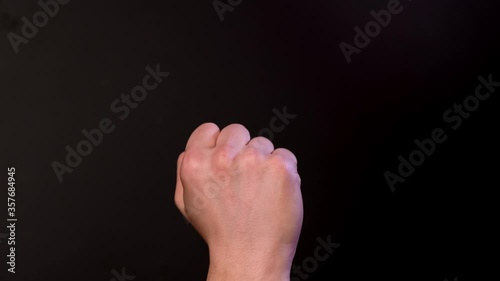 Man shows middle finger on black background. Close up